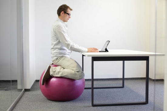 richtiges Sitzen, z.B. auf einem Gymnastikball, beugt Gesundheitsproblemen am Arbeitsplatz vor